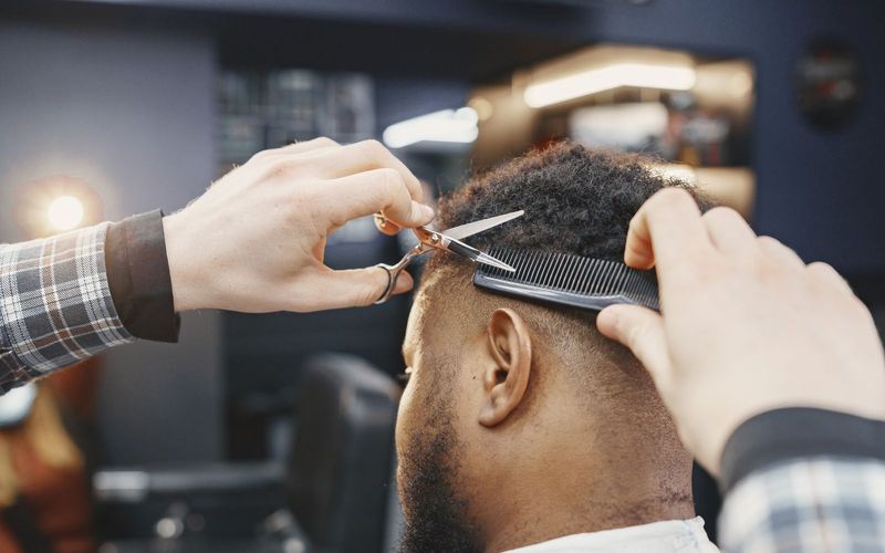 Close-up of a barber giving a haircut with scissors and comb in a modern salon